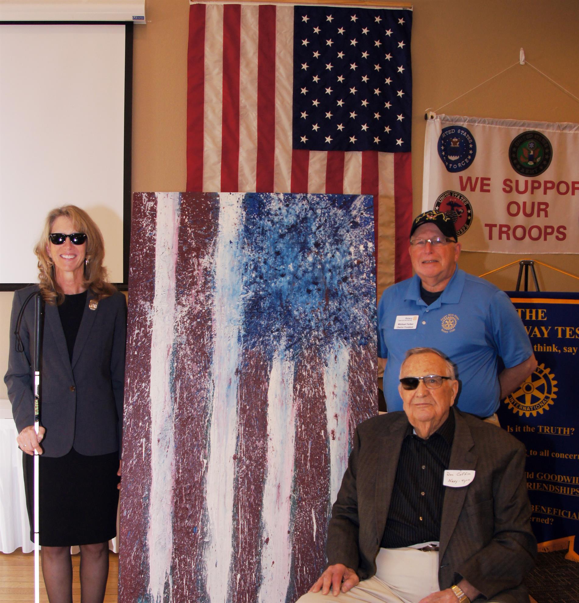 With a backdrop of the American flag and the Annie Young painting depicting the American Flag, Veterans (from left) Annie Young, Don Coffin and Mike Ferber were honored by the Rotary Club of Eagan (Noon Club) and the Eagan Kick-Start Club for Veterans Day 2021.  A $200 certificate was given to the following charities as designated by each Veteran, Salvation Army (Coffin), Silent Warrior Project Burnsville (Young) and Can Do Canines (Ferber). Community organizations supporting Veterans were recognized, Commons on Marice, Eagan Men’s Chorus and the Rotary Club of Minnesota Veterans.  