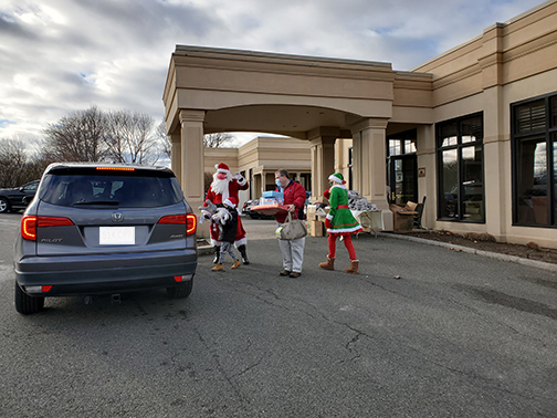 Santa and his elf greet children with gifts.
