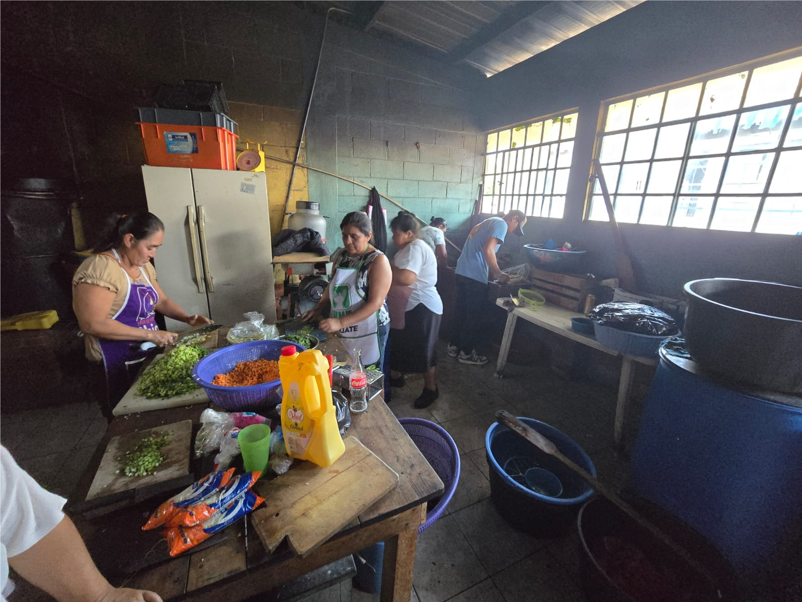 Women preparing food in the original school kitchen, with limited counter space