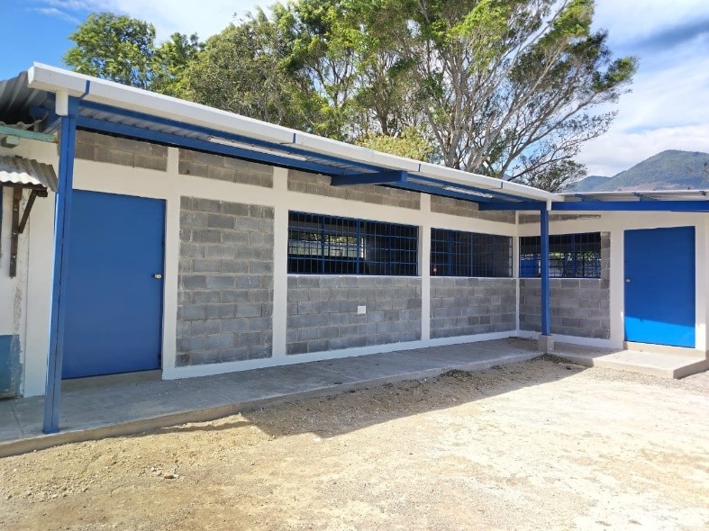 Newly constructed school classrooms with blue doors and corrugated metal roof