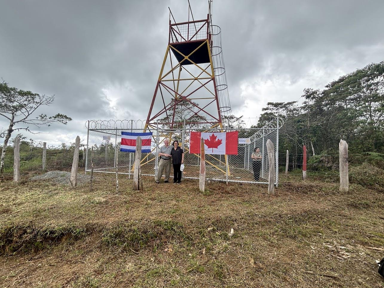 A red and yellow fire prevention lookout tower in southern Costa Rica, with the Costa Rican and Canadian flags displayed at the entrance