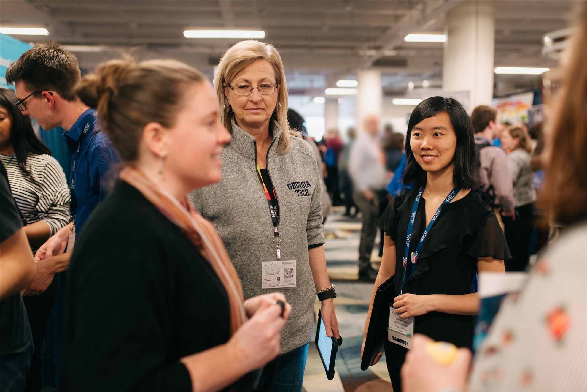 From Conference 2019, Image of people smiling in a conference area and talking