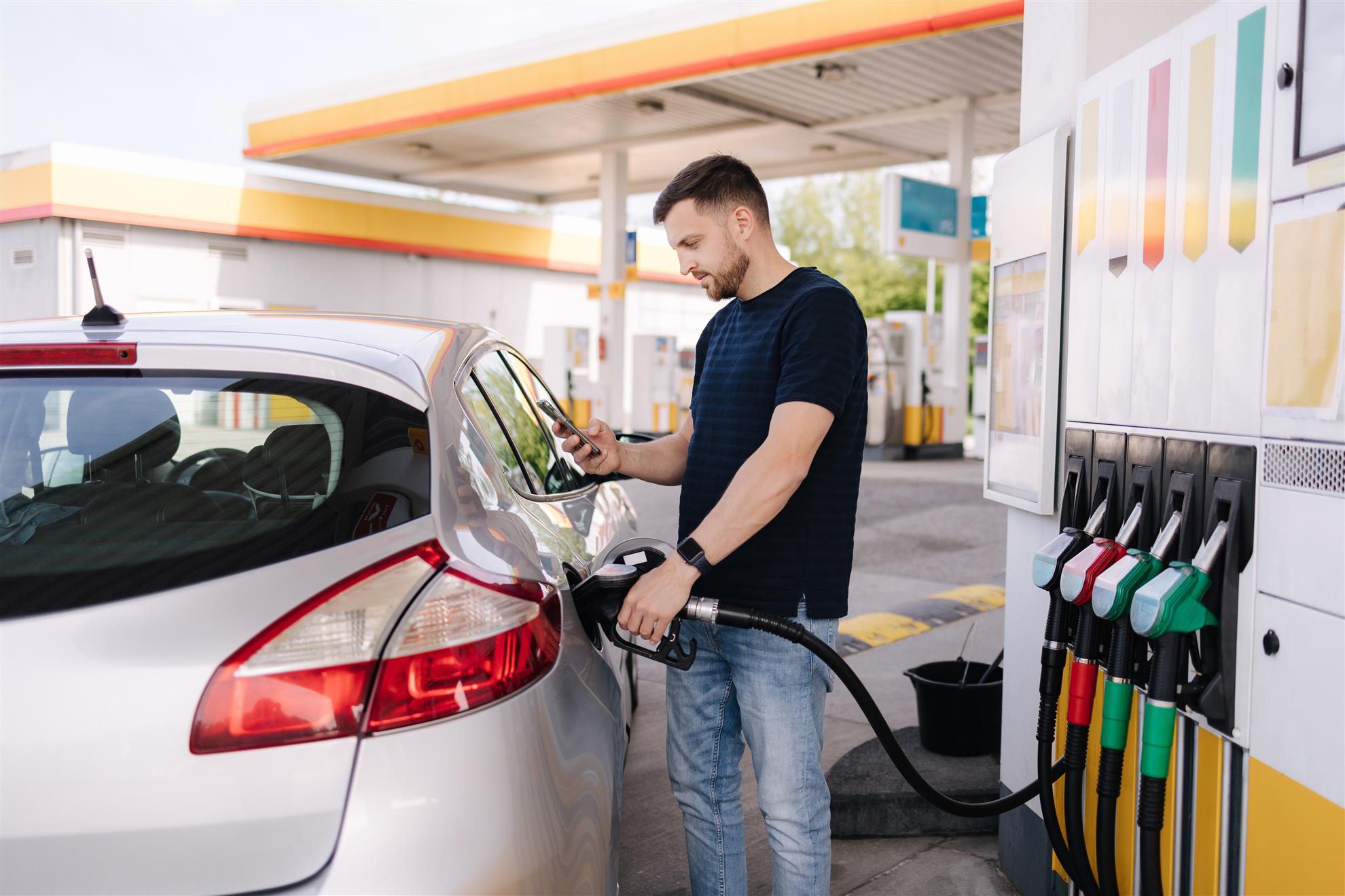 Man pumping gas into his white vehicle.