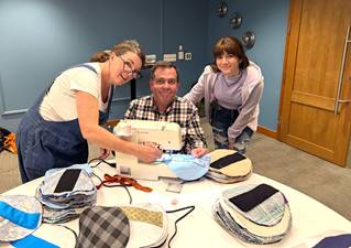 A group of people sewing on a tableDescription automatically generated