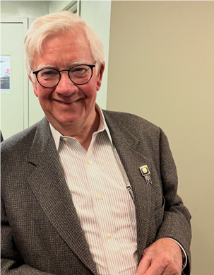 A person wearing glasses and a jacketDescription automatically generated