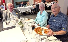 A group of people eating pizzaDescription automatically generated