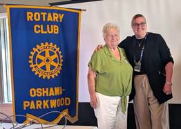 A person and person standing next to a bannerDescription automatically generated