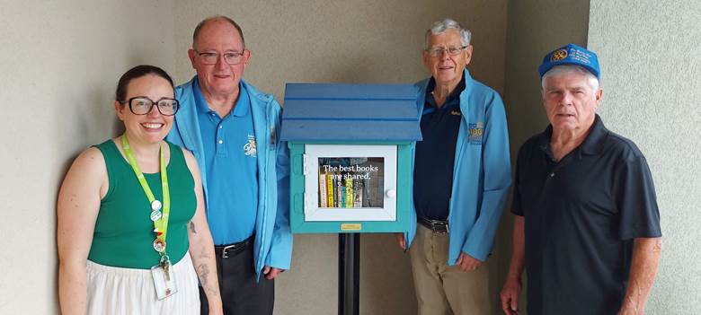 A group of people standing next to a small blue boxAI-generated content may be incorrect.